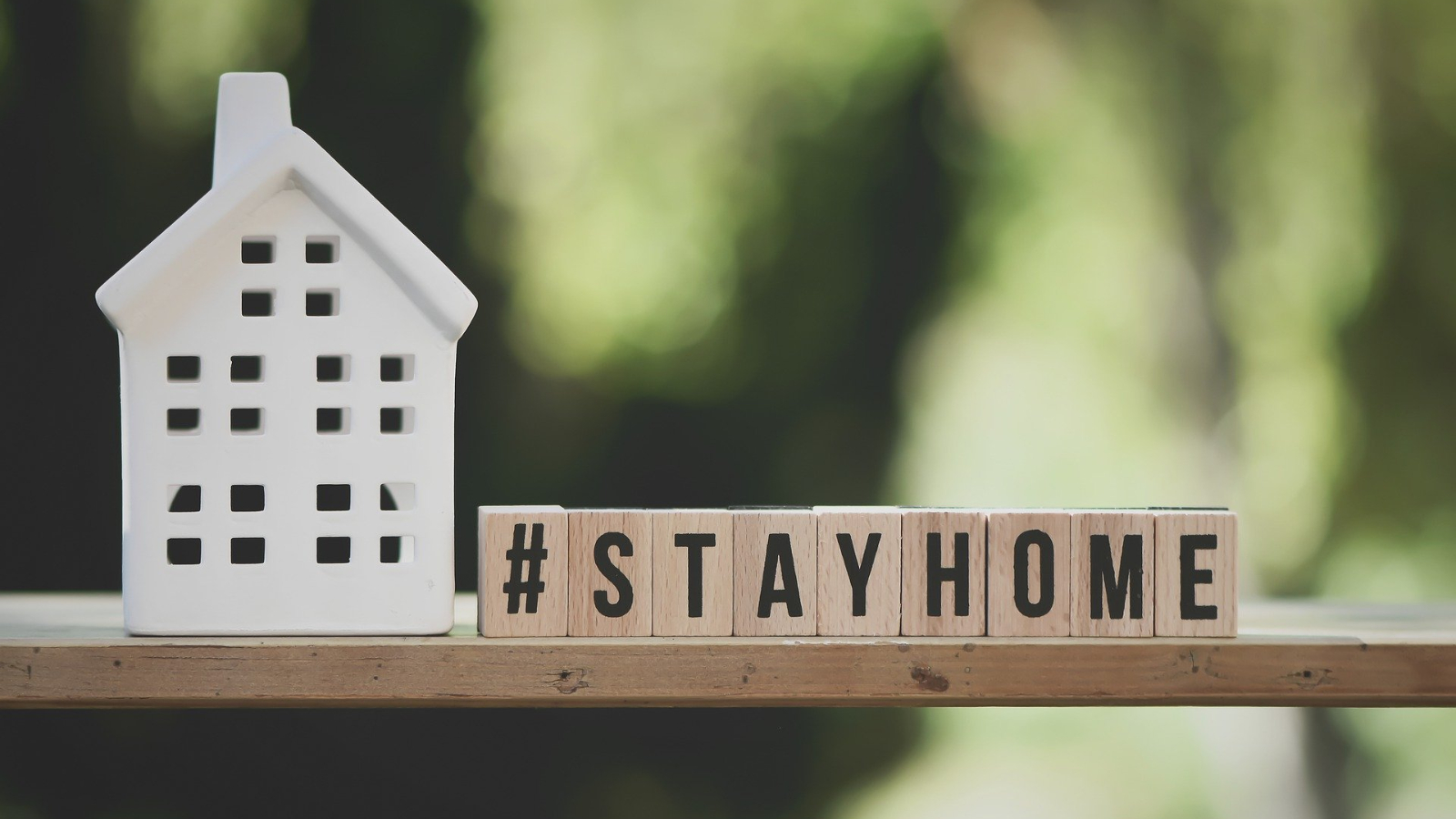 Ein haus mit Buchstabenwürfeln daneben diese ergeben '#STAYHOME'