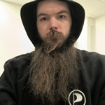 Mensch mit Bart im Schwarzen Kapuzenpulli mit Piratenlogo