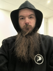 Mensch mit Bart im Schwarzen Kapuzenpulli mit Piratenlogo